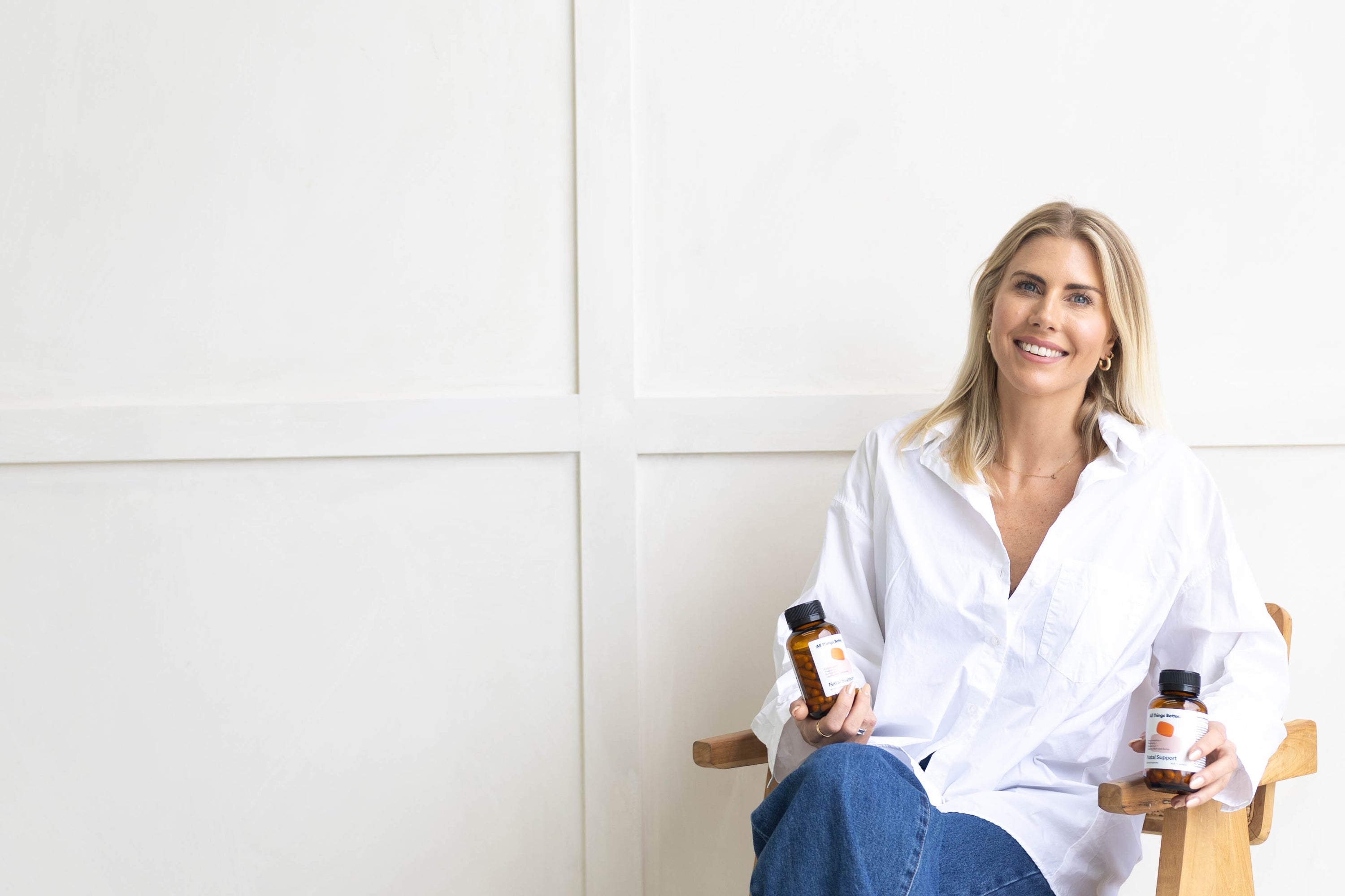 Woman holding two bottles of All Things Better natal support